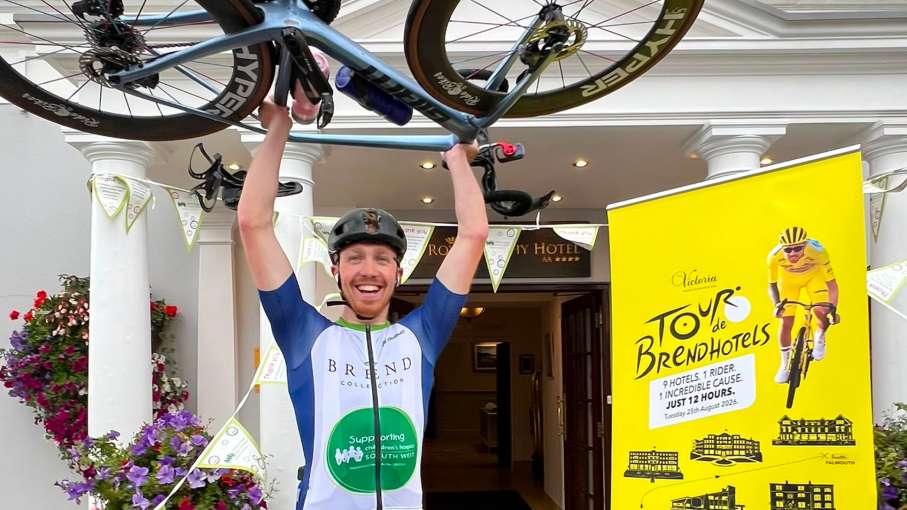 Aidan lifting bike in the air outside The Royal Duchy Hotel