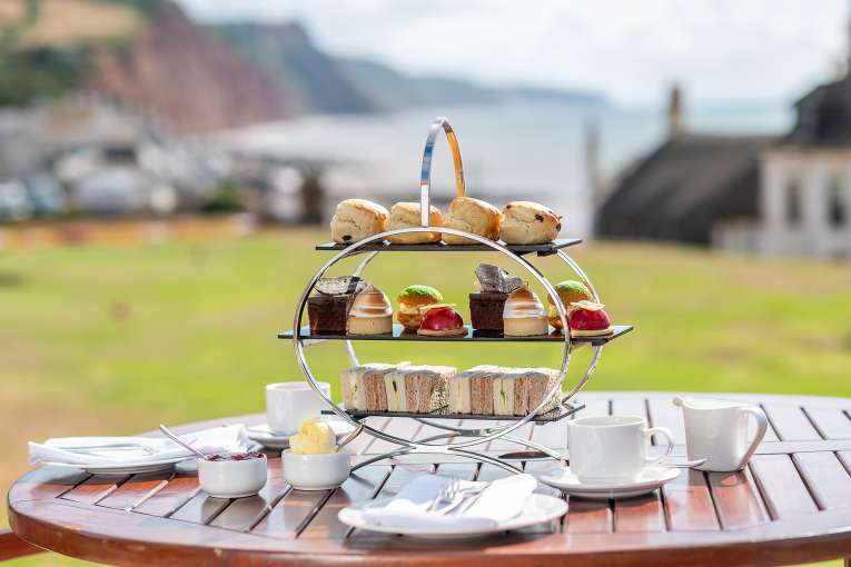 Afternoon Tea on a wooden table with Jurassic Coast in the background