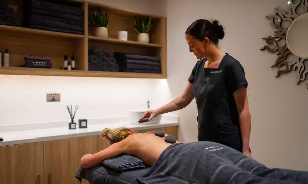 Spa therapist giving a hot stone massage 