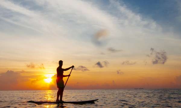 A paddle boarder on calm seas at sunset