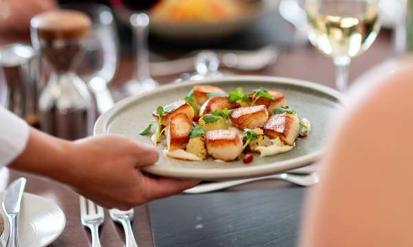 Hand serving Scallop dish in The White Room