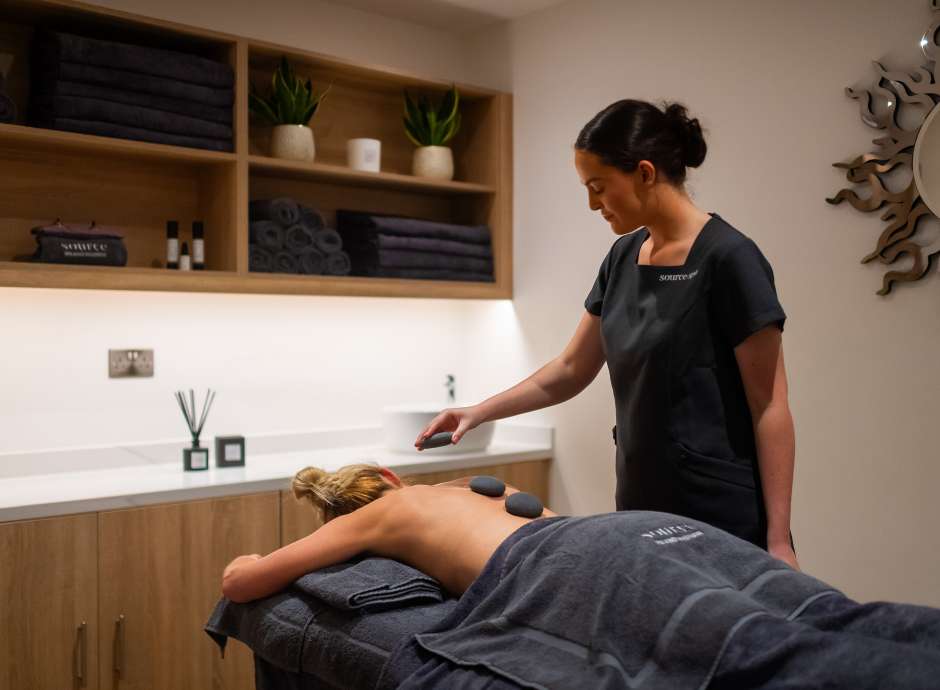 Spa therapist giving a hot stone massage 