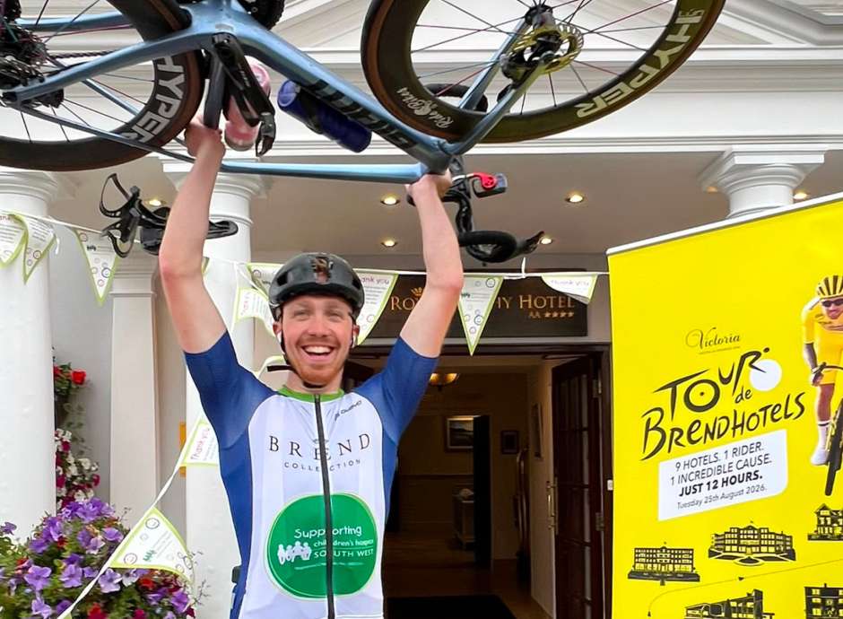 Aidan lifting bike in the air outside The Royal Duchy Hotel