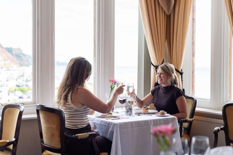 Two women in The Jubilee Restaurant doing cheers with glasses